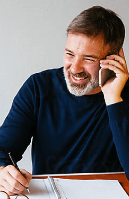 A man using the phone, sitting at his desk.