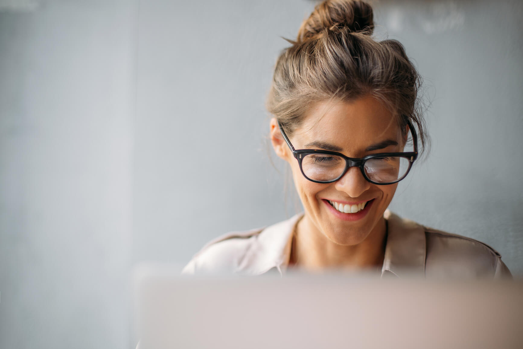 A woman smiling at her laptop.